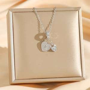 Collier double cœur argenté avec cristaux pavés présenté sur un écrin de bijoux