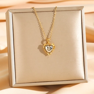 Collana con ciondolo a cuore bicolore e bordo dorato su una scatola per gioielli