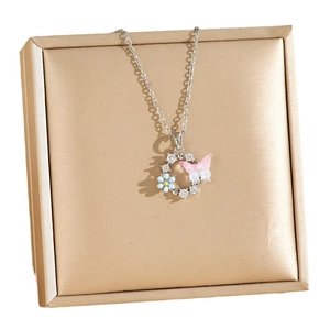 Collier papillon argenté avec perles et zircons présenté sur une boîte à bijoux