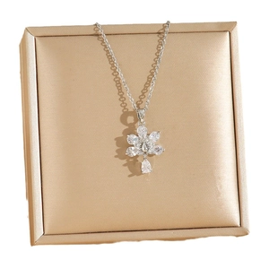 Élégant collier paon argenté avec pendentif fleur en cristal sur un coffret à bijoux de luxe