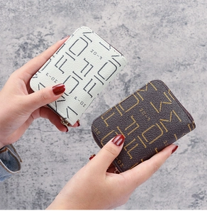 Détail des porte-cartes en cuir avec motif FIOM, fermeture éclair dorée et fentes