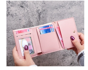 Pink matte leather tri-fold wallet detail showing multiple card slots and clear ID window