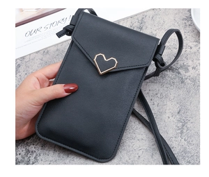 Dettaglio borsa porta cellulare nera con fibbia a cuore dorata e tracolla sottile