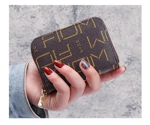 Gros plan d'un petit porte-monnaie marron foncé zippé avec logo FDM et texture grainée
