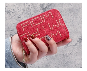 Détail d'un porte-cartes en cuir grainé rouge avec lettres dorées et fermeture