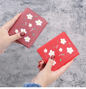 Détail de portefeuilles trifold en similicuir rose et rouge avec motifs floraux