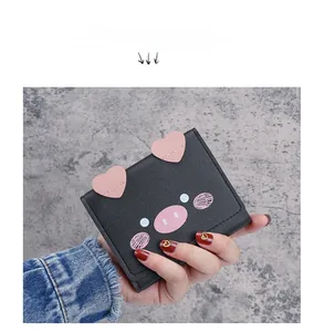 Detail of a cute black bi-fold wallet with 3D pink heart ears and cartoon pig design
