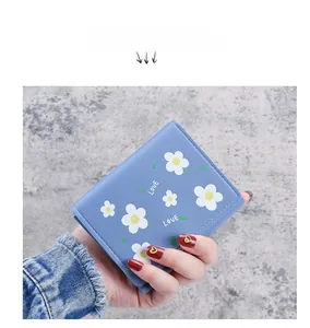 Gros plan du portefeuille trifold bleu clair avec motifs marguerites tenu à la main