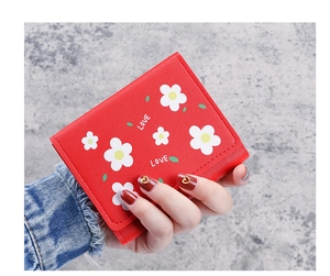 Détail d'un portefeuille rouge à trois volets avec marguerites et imprimé LOVE