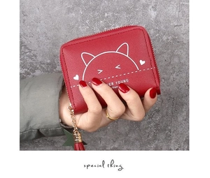 Close-up of red zip-around wallet with cute cat print and stylish red tassel