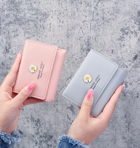 Close-up of three-fold women's wallets with daisy metal charms in pink and blue
