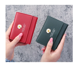 Close-up of red and green tri-fold daisy wallets held to show compact size and texture