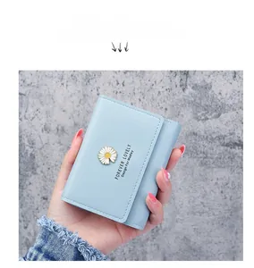 Detail of light blue tri-fold leather wallet with white daisy ornament and textured finish