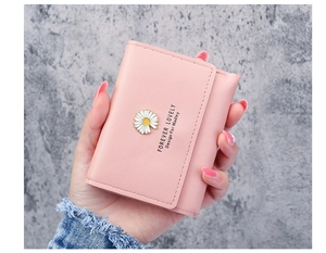 Close-up of a pink tri-fold daisy wallet featuring card slots and a metal flower emblem