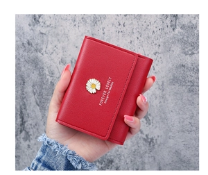 Detail of red daisy wallet with floral metal logo and Forever Lovely print in hand