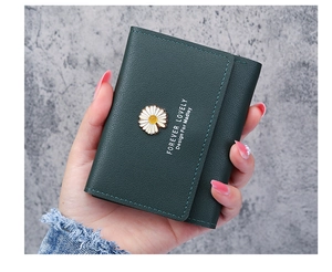 Close-up of a dark green pebble leather tri-fold wallet with a daisy buckle and gold text