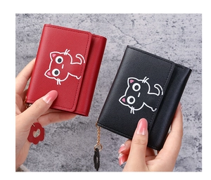Detail of red and black tri-fold wallets featuring cartoon cat pattern and flower charm