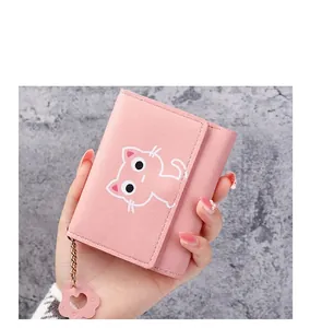 Detailed view of pink tri-fold wallet with cat pattern and paw pendant in hand