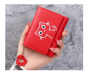 Close-up of red tri-fold wallet featuring cartoon cat print and cute paw pendant charm