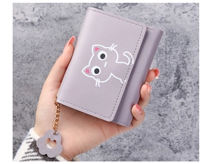 Detail of lavender cat wallet in hand showing portable trifold design and paw pendant