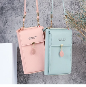 Close-up of small crossbody phone bags in pink and green with leaf zipper detail