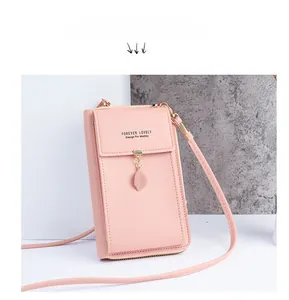 Detailed view of pink crossbody phone bag with leaf charm and elegant gold zipper