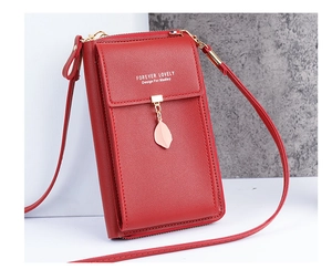 Detail of red vertical crossbody phone bag with leaf charm and gold metallic zipper
