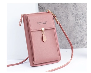 Detail of pink faux leather crossbody phone bag with metal leaf pendant and long strap