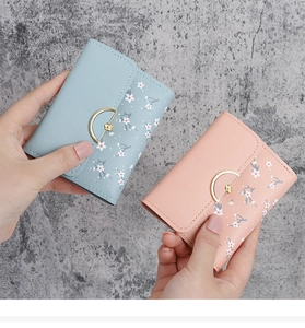 Close-up of small floral leather wallets in light blue and pink with metal buckles