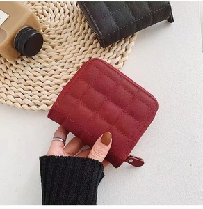 Gros plan d'un mini portefeuille matelassé rouge en cuir avec une fermeture éclair en métal