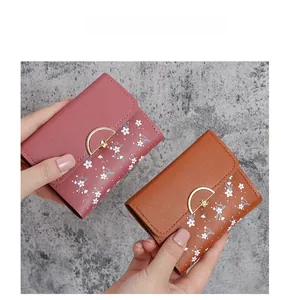 Close-up of trifold wallets in pink and brown leather with elegant white floral patterns