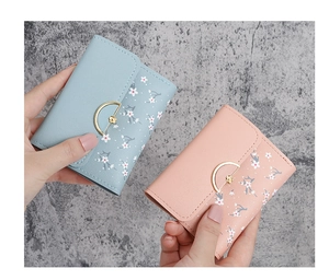 Close-up of mini wallets in light blue and pink with floral patterns and gold flower clasp
