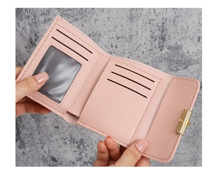 Detail of pink tri-fold wallet showing card slots and gold twist lock closure