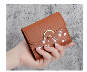 Detailed view of a brown pebbled leather wallet with floral print and gold floral clasp