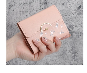 Close-up of a pink mini wallet featuring small white floral patterns and a gold metal clasp