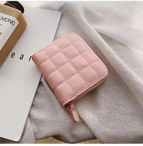 Gros plan du mini portefeuille rose en similicuir matelassé avec fermeture éclair sûre