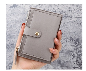 Close-up of slim grey PU leather card holder with gold zipper and snap button in hand