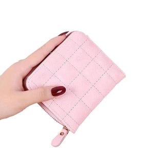 Mini portefeuille rose matelassé en cuir avec fermeture éclair tenu à la main