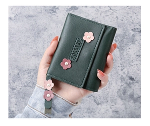 Détail d'un portefeuille vert en similicuir plié en trois avec décoration florale