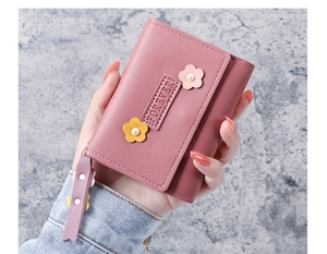 Détail du portefeuille en cuir rose avec pétales 3D, perle fantaisie et tirette zip