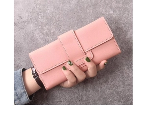 Gros plan sur la texture en cuir rose grainé et les coutures du portefeuille long pour femme