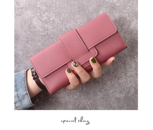 Gros plan du long portefeuille en similicuir rose avec lanière et surpiqûres blanches
