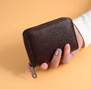 Détail d'un porte-cartes en cuir grainé marron foncé avec fermeture éclair métallique