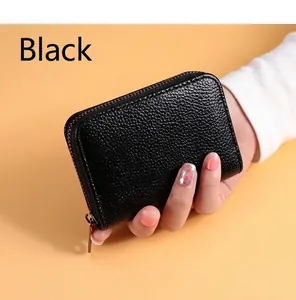 Gros plan d'un porte-cartes en cuir noir à motif litchi avec fermeture éclair à la main