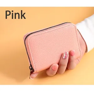 Petit porte-cartes rose en similicuir grainé avec fermeture éclair tenu à la main