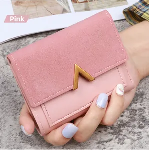 Detail of pink tri-fold faux leather wallet with gold V-shaped metal hardware accessory