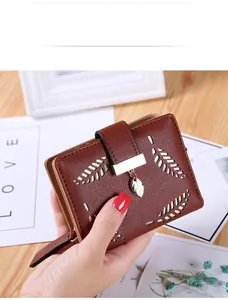 Detail of a brown short wallet for women featuring a hollow leaf pattern and metal buckle