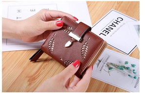 Close-up of brown PU leather wallet featuring laser-cut leaf patterns and a metal pendant