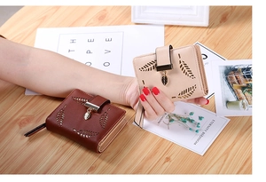 Detail of laser-cut leaf pattern on brown and beige PU leather wallets on wood