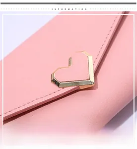 Macro detail of pink long wallet featuring a gold heart-shaped metal buckle ornament